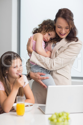 Well dressed mother with daughters and laptop in kitchen