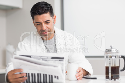 Serious man with coffee cup reading newspaper