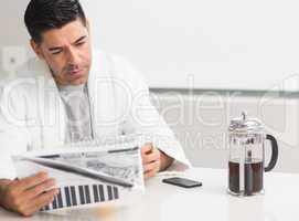 Serious man reading newspaper in kitchen