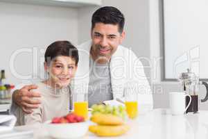 Young son with father having breakfast in kitchen