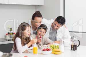 Happy kids enjoying breakfast with parents in kitchen