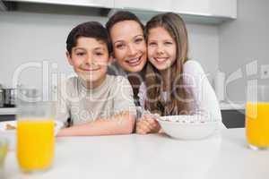 Portrait of a smiling mother with young kids in kitchen