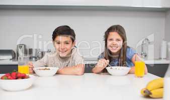 Young siblings enjoying breakfast in kitchen