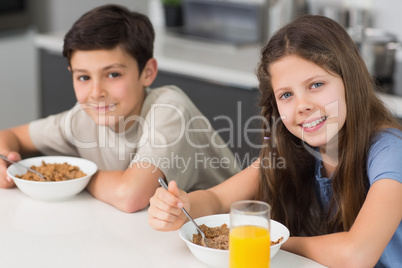 Smiling young siblings enjoying breakfast in kitchen