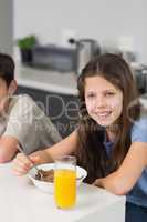 Portrait of two smiling siblings enjoying breakfast