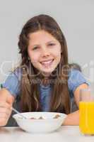 Smiling young girl enjoying breakfast in kitchen