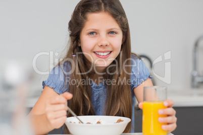 Smiling young girl enjoying breakfast in kitchen