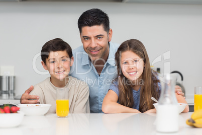 Kids enjoying breakfast with father in kitchen