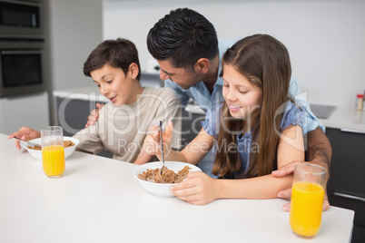 Happy young kids enjoying breakfast with father