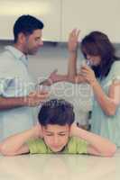 Sad young boy covering ears while parents quarreling