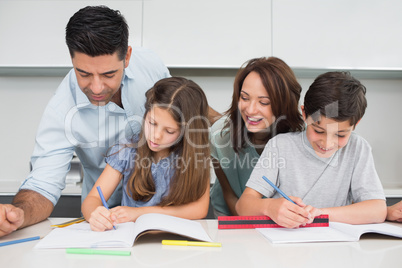 Couple helping kids with their homework in kitchen