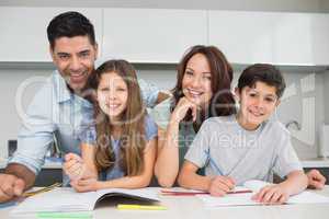 Smiling couple helping kids with homework at home