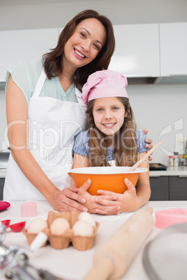 Portrait of girl and mother preparing cookies in kitchen