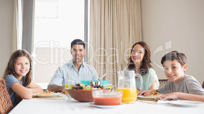 Portrait of happy family of four sitting at dining table