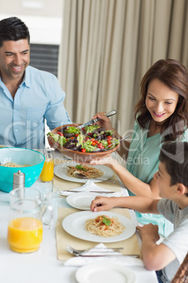 Happy family of three sitting at dining table