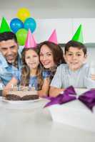 Family of four with cake and gifts at birthday party