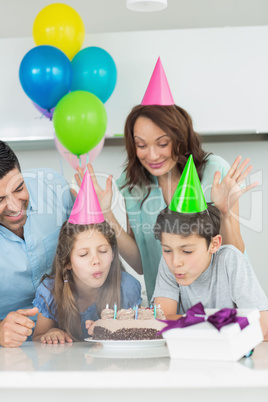 Family of four blowing cake