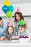 Family of four blowing cake