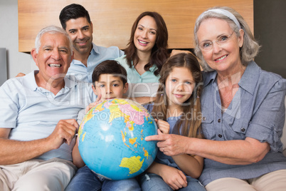 Extended family sitting on sofa with globe in living room