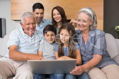 Extended family using laptop on sofa in living room