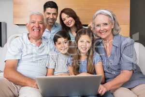 Extended family using laptop on sofa in living room