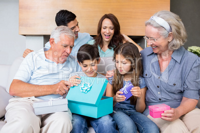 Extended family sitting on sofa with gift boxes in living room
