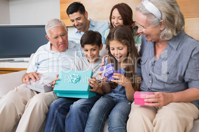 Extended family sitting on sofa with gift boxes in living room