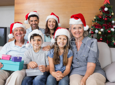 Extended family in Christmas hats with gift boxes in living room