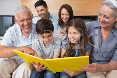 Extended family looking at album photo in living room