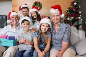 Extended family in Christmas hats with gift boxes in living room