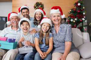 Extended family in Christmas hats with gift boxes in living room