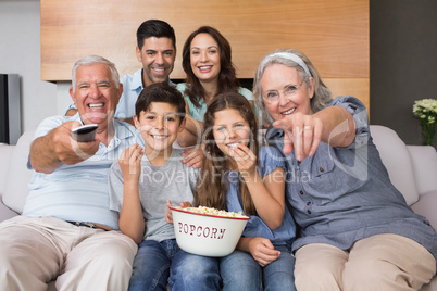 Portrait of happy extended family watching tv in living room