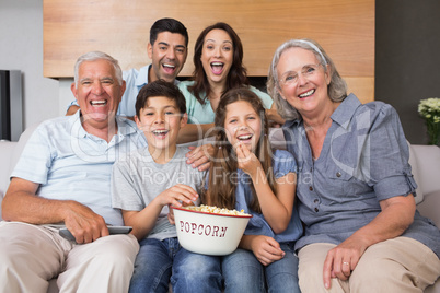 Portrait of happy extended family watching tv in living room