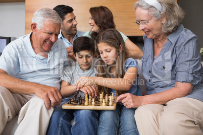 Happy extended family playing chess in the living room