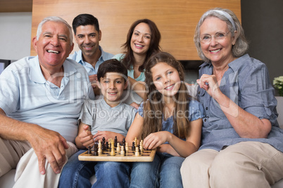 Portrait of happy extended family playing chess in living room