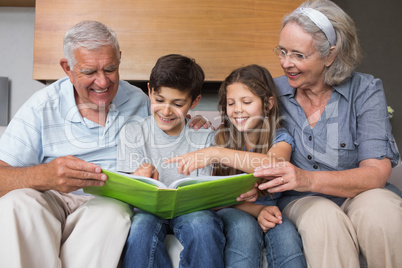 Happy grandparents and grandkids looking at album photo