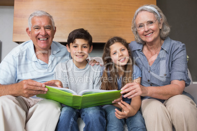 Portrait of grandparents and grandkids looking at album photo