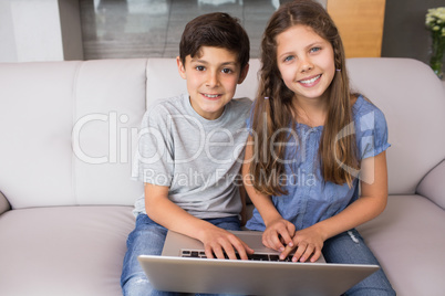 Portrait of young siblings using laptop in the living room