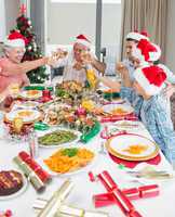 Family in santas hats toasting wine glasses at dining table