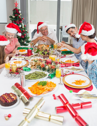 Happy family in santas hats enjoying Christmas dinner