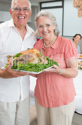 Portrait of senior couple holding chicken roast