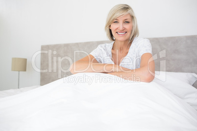 Pretty smiling mature woman sitting on bed