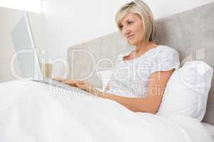Woman using laptop in bed at home