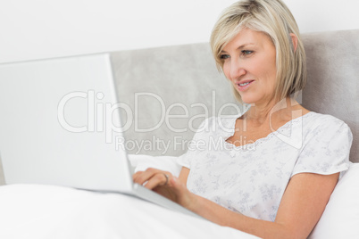 Mature woman using laptop in bed