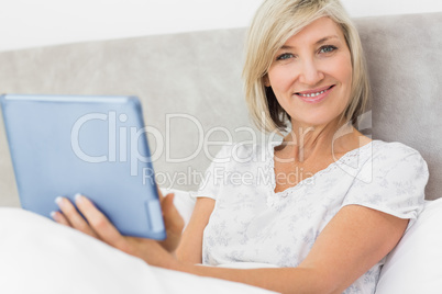 Smiling mature woman using digital tablet in bed