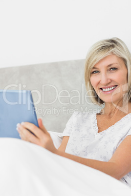 Smiling mature woman using digital tablet in bed