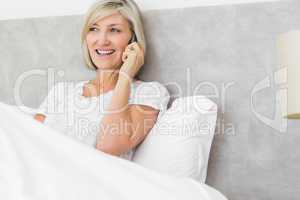 Mature woman using mobile phone in bed