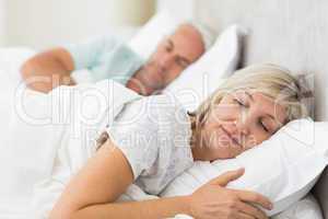 Mature couple sleeping with eyes closed in the bed