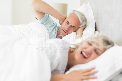 Man covering ears while woman shouting in bed