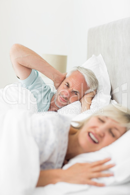Man covering ears while woman shouting in bed